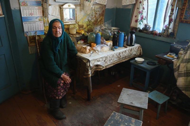 PARUSHEV, UKRAINE - SEPTEMBER 30: Marya Kindrativna, 80, sits in the house she shares with her husband Ivan Semenyuk inside the Chernobyl Exclusion Zone on September 30, 2015 in Parushev, Ukraine. Parushev, a village that before 1986 had a population of about 600, lies 13km from the former Chernobyl nuclear power plant, where in 1986 workers inadvertantly caused reactor number four to explode, creating the worst nuclear accident in history. Authorities evacuated 120,000 people, including the residents of Parushev. Semenyuk and Kindrativna, along with a few other elderly residents, were allowed to return a year later and have lived there ever since. While radiation levels in Parushev are negligible, the village lies in the Chernobyl Exclusion Zone that covers 2,600 square kilometers and where only a few elderly people have dared to return. Semenyuk grows corn, beets, potatoes, cucumbers, tomatoes and pumpkins, forages for mushrooms in nearby forests and has a stall with 13 chickens. A bus selling provisions still comes by around once a month, though visits by a medical team to Parushev have ceased. (Photo by Sean Gallup/Getty Images)