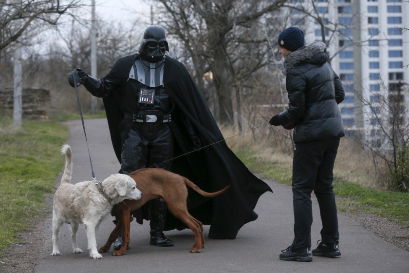 Darth Mykolaiovych Vader, who is dressed as the Star Wars character Darth Vader, poses for a picture as he speaks to a woman while walking his dog in a park in Odessa, Ukraine, December 3, 2015. Darth Vader was bent on galactic domination, but his Ukrainian namesake enjoys more mundane pursuits: local politics, walking the family dog and a spot of embroidery. The Ukrainian citizen, who has changed his name to Darth Mykolaiovych Vader, ran for the post of local mayor in October, his political backers dressed as Stormtroopers. In his trademark black outfit, he is a regular sight around Odessa, a major port city on southern Ukraine's Black Sea coast. REUTERS/Valentyn Ogirenko PICTURE 3 OF 22 - SEARCH "VALENTYN VADER" FOR ALL IMAGES - RTX1Y7XZ