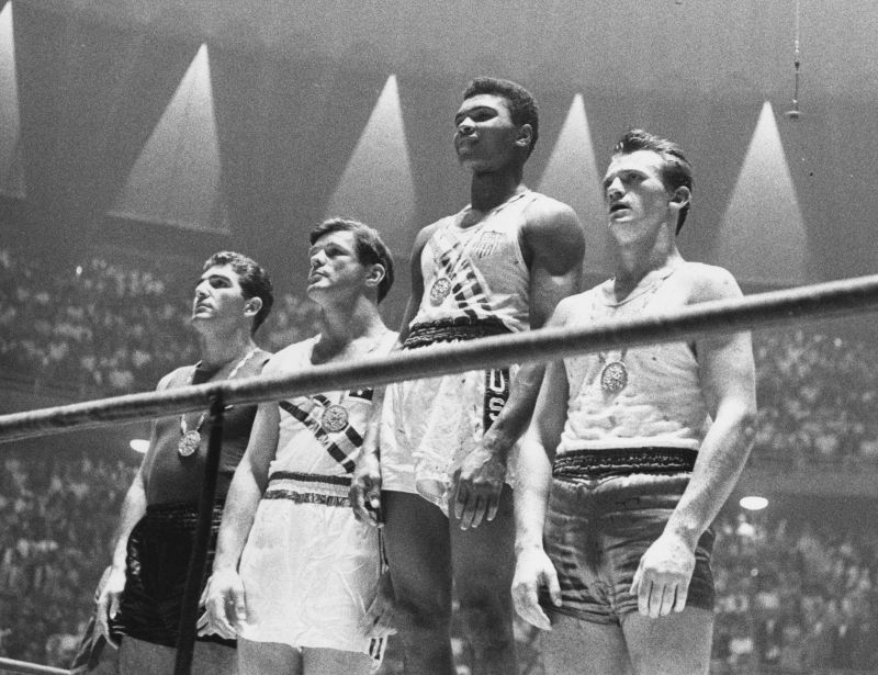 The winners of the 1960 Olympic medals for light heavyweight boxing on the winners' podium at Rome: Cassius Clay (now Muhammad Ali) (C), gold; Zbigniew Pietrzykowski of Poland (R), silver; and Giulio Saraudi (Italy) and Anthony Madigan (Australia), joint bronze. (Photo by Central Press/Getty Images)