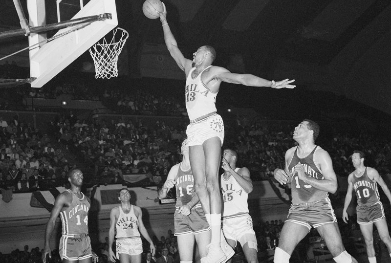 (Original Caption) Philadelphia: 76ers' Wilt Chamberlain, jumps high as Cincinnati Royal, Jerry Lucas (16) and Wayne Embry (15) can only look on during first period action, March 20th at convention hall.