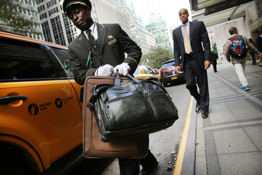 NEW YORK, NY - OCTOBER 06: An employee helps a guest with his bags at the Waldorf Astoria, the landmark New York hotel, is viewed on October 6, 2014 in New York City. It was announced October 6, that Hilton Worldwide will sell the Waldorf to the Beijing-based Anbang Insurance Group for $1.95 billion. As part of the deal the Waldorf will undergo a major renovation. The Park Avenue hotel opened on October 1, 1931, and claimed to be the biggest hotel in the world at the time, attracting movie stars, politicians and the wealthy. (Photo by Spencer Platt/Getty Images)
