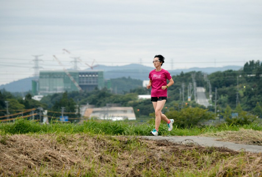 Masae Endo, 50, jogs the town where the evacuation order was lifted on September 5, 2015 in Naraha, Japan. The Fukushima Daini Nuclear Power Plant can be seen in the distance. (The Asahi Shimbun via Getty Images)