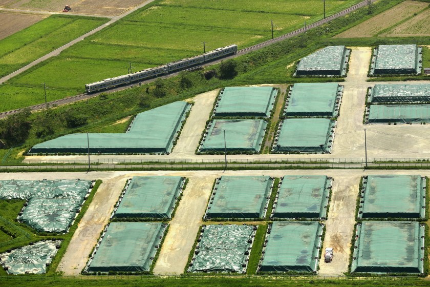 NARAHA, JAPAN - JUNE 01: (CHINA OUT, SOUTH KOREA OUT) In this aerial image, a Joban line train runs past a temporary storage site of the radiation contaiminated soil as the train operation restarted between Hirono and Tatsuno on June 1, 2014 in Naraha, Fukushima, Japan. The government plans to lift the mandatory evacuation order for Naraha, allowing residents to return to the town hit hard by the Fukushima nuclear disaster as early as spring 2015. (Photo by The Asahi Shimbun via Getty Images)