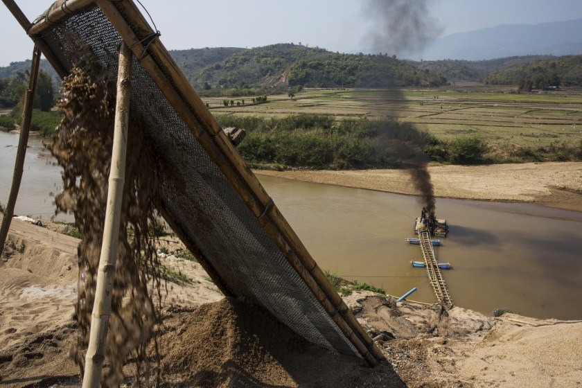 Slurry pours through a filter from a makeshift pipeline on the banks of a river as smoke billows from the rig at a sand dredging site near Kengtung, Shan State, Myanmar, on Thursday, Feb. 18, 2016. The recently-elected National League for Democracy has been vague about its plans for the country. Its economic platform pledged to do things such as expand the tax base and increase foreign investment, without saying how. (Taylor Weidman/Bloomberg via Getty Images)