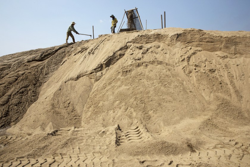 Slurry pours through a filter from a makeshift pipeline as workers shovel sand at a sand dredging site near Kengtung, Shan State, Myanmar, on Thursday, Feb. 18, 2016. The recently-elected National League for Democracy has been vague about its plans for the country. Its economic platform pledged to do things such as expand the tax base and increase foreign investment, without saying how. (Taylor Weidman/Bloomberg via Getty Images)