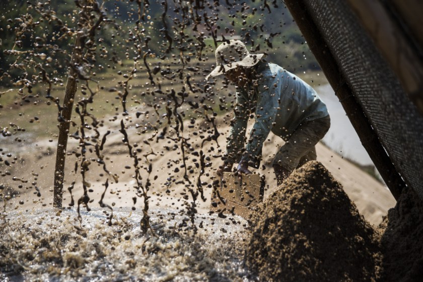 A worker directs the flow of slurry from a makeshift pipeline pouring through a filter on the banks of a river at a sand dredging site near Kengtung, Shan State, Myanmar, on Thursday, Feb. 18, 2016. The recently-elected National League for Democracy has been vague about its plans for the country. Its economic platform pledged to do things such as expand the tax base and increase foreign investment, without saying how. (Taylor Weidman/Bloomberg via Getty Images)