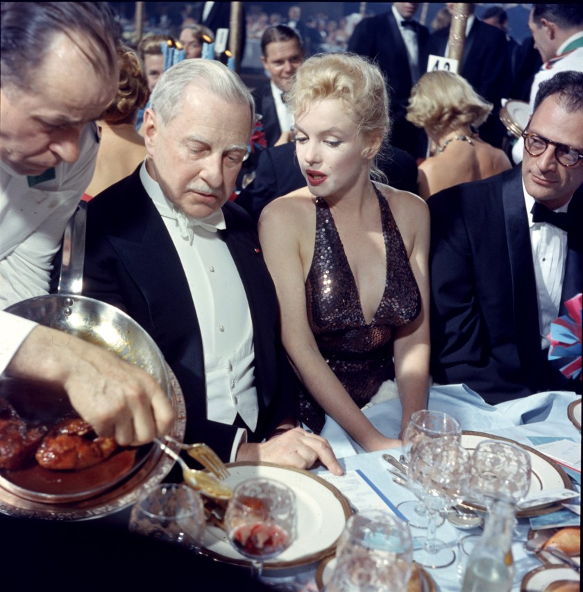 A waiter serves food to American finacier Winthrop Aldridge (1885 - 1974), who sits beside married couple, actress Marilyn Monroe (born Norma Jeane Mortenson, 1926 - 1962) and playwright Arthur Miller (1915 - 2005), during the 'April in Paris Ball' at the Waldorf Astoria, New York, New York, April 11, 1957. (Photo by Peter Stackpole/The LIFE Picture Collection/Getty Images)