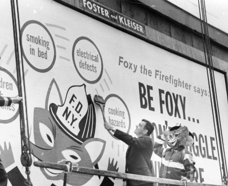 What Smokey the Bear is to the prevention of forest fires, City officials hope Foxy the Fireman will be to human safety. Fire Commissioner Thompson (c) puts the finishing touches to one of 250 billboard signs posted around the city to warn against home fire hazarsd. Looking on are Asst. Chief Charles McKeogh (l) and Foxy himself, played by fireman Barney Schmeltzer. (Photo by William Jacobellis/New York Post Archives / (c) NYP Holdings, Inc. via Getty Images)