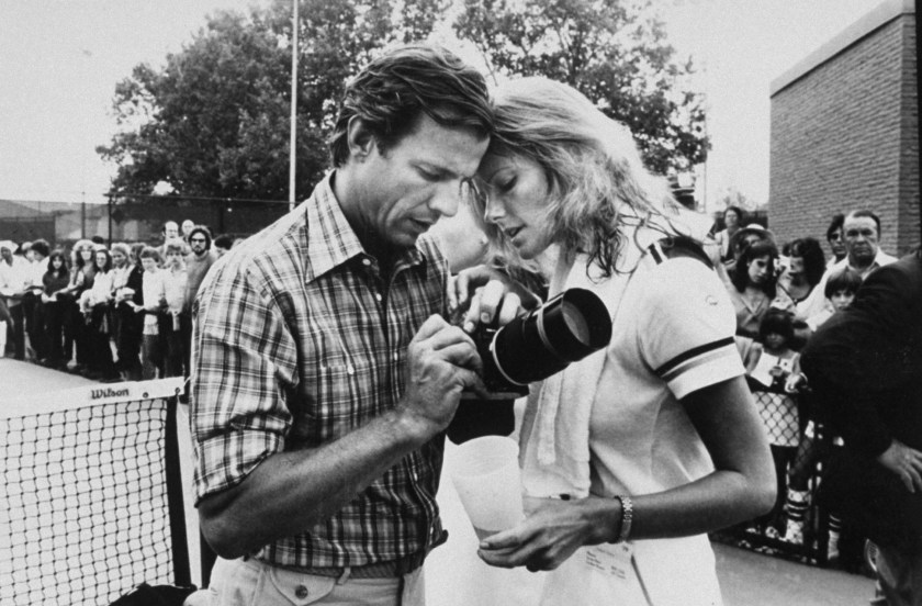 Photographer Peter Beard (L) holding camera with model/wife Cheryl Tiegs (R) on tennis court, as crowd watches behind fence. (Robin Platzer/Twin Images/The LIFE Images Collection/Getty Images)