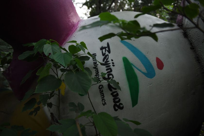 This photo taken on July 26, 2016 shows Fu Niu Lele, the mascot for the 2008 Beijing Paralympic Games, lying amongst trees behind an abandoned, never-completed mall in Beijing. Photographed weeks before the 2016 Olympics open in Rio, the fallen mascots are a reminder of the high costs of hosting the event. Their derelict state reflects the challenges that China has faced in finding new uses for its Olympic investments, with many venues falling into disrepair and some construction projects left incomplete. / AFP / GREG BAKER / TO GO WITH STORY Oly-2016-Rio-China-mascots-offbeat (Photo credit should read GREG BAKER/AFP/Getty Images)