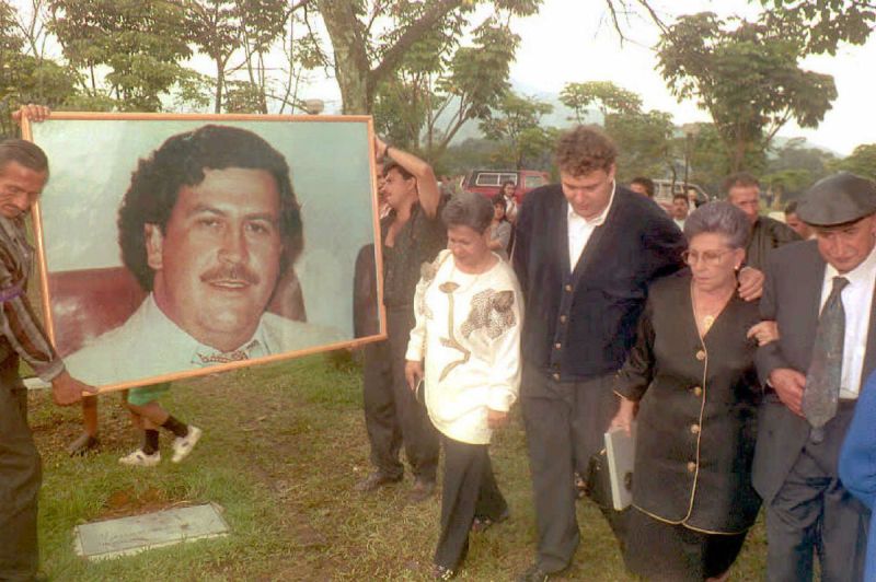 Hermilda de Escobar (2nd-R), mother of Medellin drug cartel kingpin Pablo Escobar (portrait), walks with friends and relatives to Escobar's tomb to celebrate the first anniversary of his death. Escobar was killed by Colombian special forces after being discovered hiding in a house in Medellin. (COLOR KEY: Trees are green.) (Photo credit should read GUILLERMO TAPIA/AFP/Getty Images)