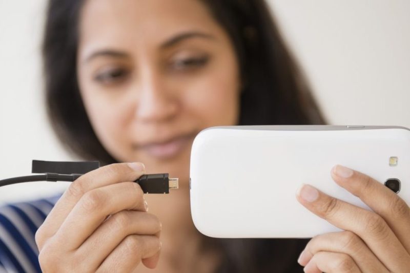 Close up of Asian woman connecting cell phone to battery