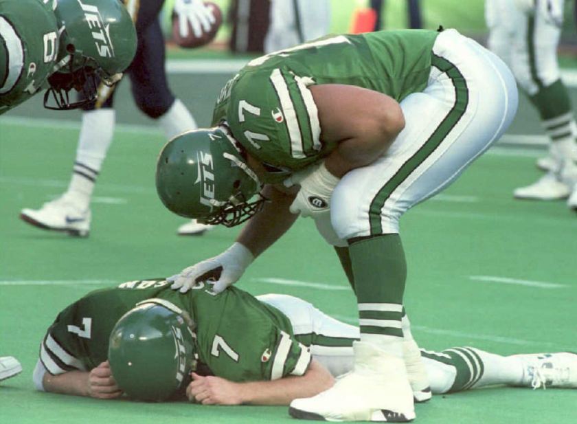 New York Jets' Matt Willig (R) and Dwayne White (L) check on their quarterback Boomer Esiason who was knocked down, and suffered a concussion, after throwing an incomplete pass in the second quarter at Giants Stadium 18 December 1994. Esiason had to leave the game and was replaced by Jack Trudeau. (Henny Ray Abrams/AFP/Getty Images)