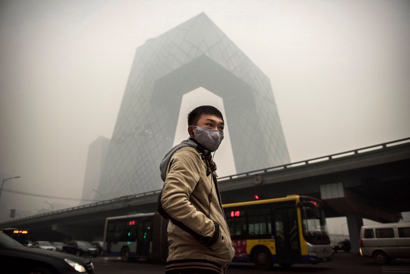 A Chinese man wears a mask as he waits to cross the road near the CCTV building during heavy smog on November 29, 2014 in Beijing, China. United States President Barack Obama and China's president Xi Jinping agreed on a plan to limit carbon emissions by their countries, which are the world's two biggest polluters, at a summit in Beijing earlier this month. (Kevin Frayer/Getty Images)