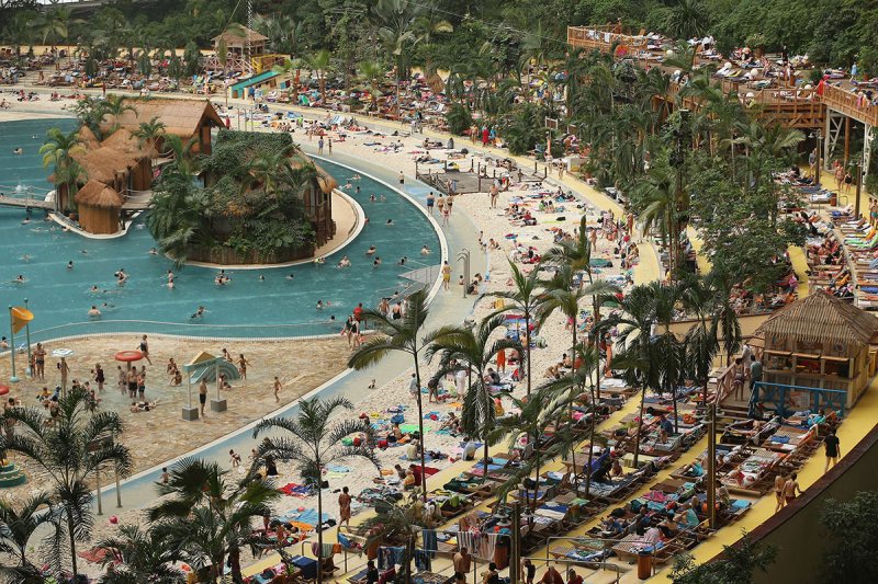KRAUSNICK, GERMANY - FEBRUARY 15: Visitors lounge at the "South Sea" beach at the Tropical Islands indoor resort on February 15, 2013 in Krausnick, Germany. Located on the site of a former Soviet military air base, the resort occupies a hangar built originally to house airships designed to haul long-distance cargo. Tropical Islands opened to the public in 2004 and offers visitors a tropical getaway complete with exotic flora and fauna, a beach, lagoon, restaurants, water slide, evening shows, sauna, adventure park and overnights stays ranging from rudimentary to luxury. The hangar, which is 360 metres long, 210 metres wide and 107 metres high, is tall enough to enclose the Statue of Liberty. (Photo by Sean Gallup/Getty Images)