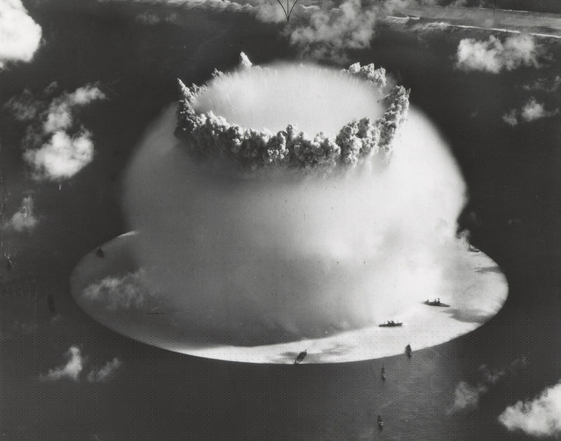 The "Baker" explosion, part of Operation Crossroads, a nuclear weapon test by the United States military at Bikini Atoll, Micronesia, on 25 July 1946. The wider, exterior cloud is actually just a condensation cloud caused by the Wilson chamber effect, and was very brief. There was no classic mushroom cloud rising to the stratosphere, but inside the condensation cloud the top of the water geyser formed a mushroom-like head called the cauliflower, which fell back into the lagoon (compare with this image, a photo taken slightly later, after the condensation cloud had cleared). The water released by the explosion was highly radioactive and contaminated many of the ships that were set up near it. Some were otherwise undamaged and sent to Hunter's Point in San Francisco, California, United States, for decontamination. Those which could not be decontaminated were sunk a number of miles off the coast of San Francisco. (Author U.S. Army Photographic Signal Corps)