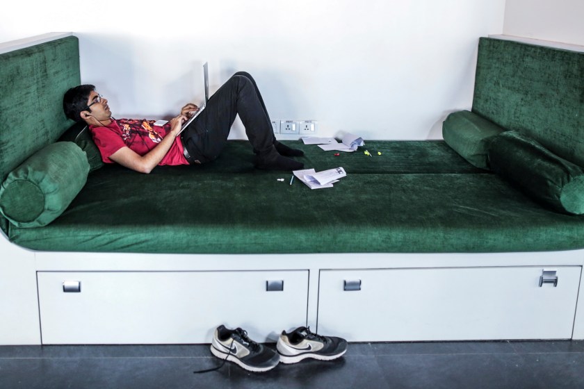 A Tiny Owl employee lies working on a laptop computer at the company's head office in Mumbai, India, on Monday, March. 9, 2015. Tiny Owl is a smartphone application that helps hungry city-dwellers scour nearby eateries for deliveries. (Dhiraj Singh/Bloomberg via Getty Images)