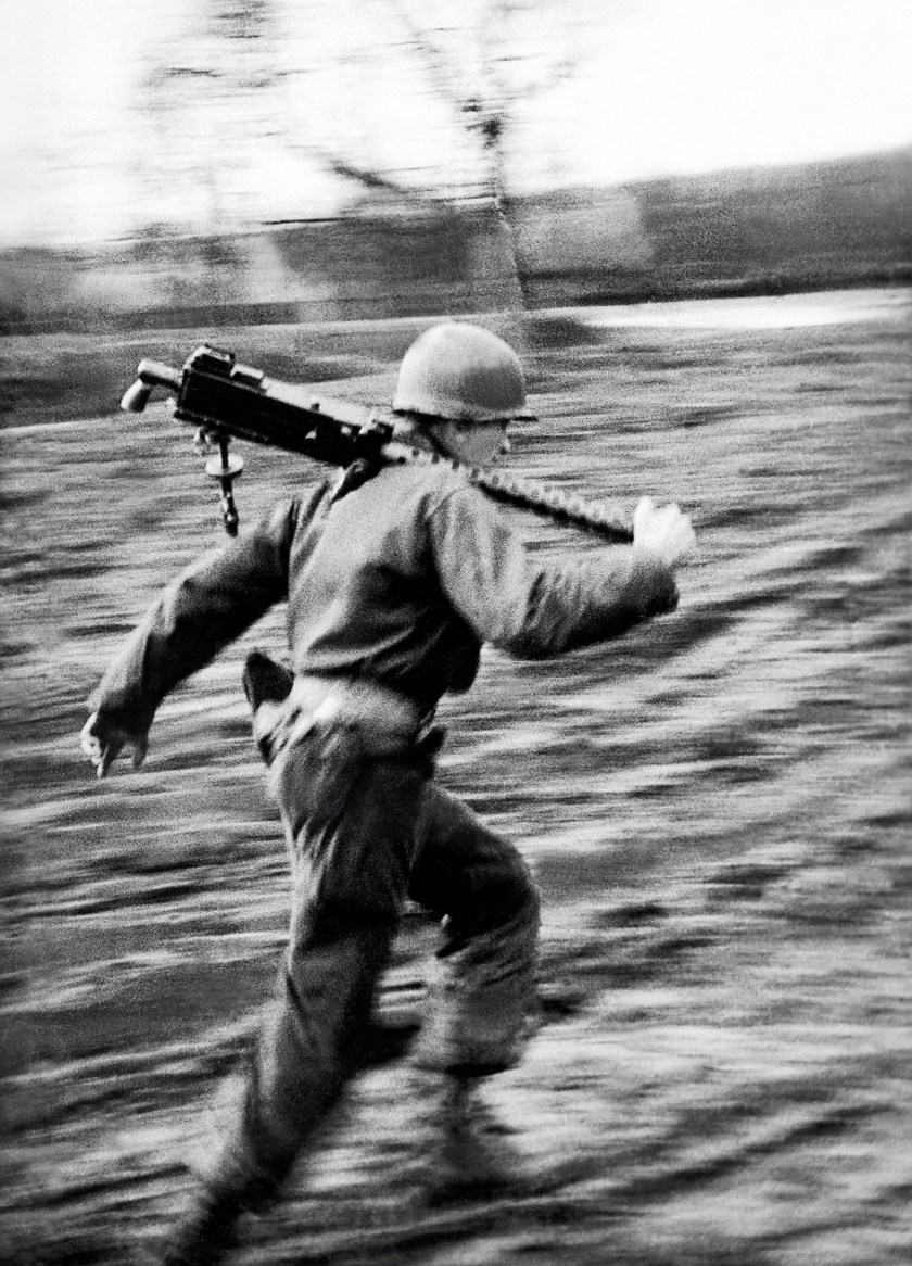An American GI runs with a machine gun during the Battle of the Bulge, Ardennes, Belgium, World War II, January 1945. (Tony Vaccaro/Getty Images)
