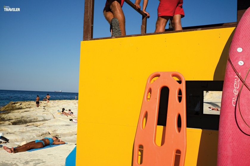 A lifeguard station on Sliema beach flaunts bold colors—and a peekaboo window. Malta sunseekers can choose between sand and stone beaches.