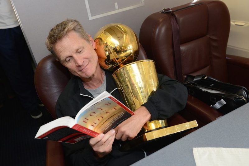OAKLAND, CA - JUNE 17: Steve Kerr of the Golden State Warriors holds the NBA trophy on the plane as the team travels home from Cleveland after winning the 2015 NBA Finals on June 17, 2015 in Oakland, California. NOTE TO USER: User expressly acknowledges and agrees that, by downloading and/or using this Photograph, user is consenting to the terms and conditions of the Getty Images License Agreement. Mandatory Copyright Notice: Copyright 2015 NBAE (Photo by Noah Graham/NBAE via Getty Images)