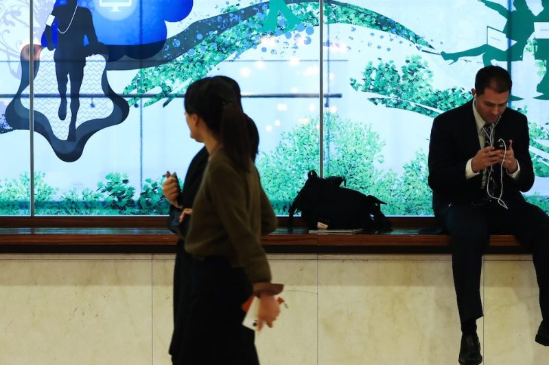 A man uses a smartphone while sitting in front of an advertisement for Samsung Electronics Co. in the COEX mall in Seoul, South Korea, on Wednesday, Jan. 4, 2017. Samsung is scheduled to release earnings results on Jan. 6. Photographer: SeongJoon Cho/Bloomberg
