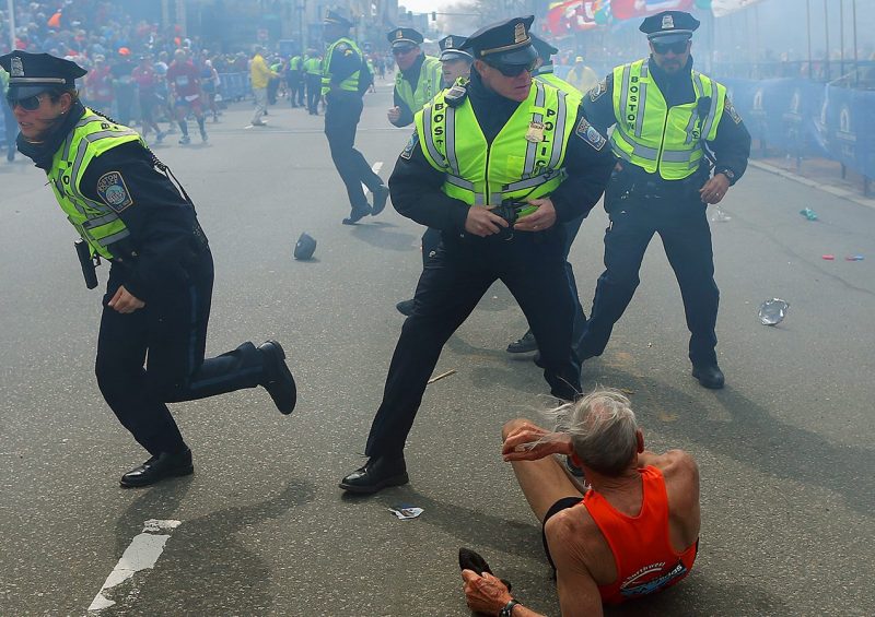 BOSTON - APRIL 15: Police officers with their guns drawn hear the second explosion down the street. The first explosion knocked down 78-year-old US marathon runner Bill Iffrig at the finish line of the 117th Boston Marathon. (Photo by John Tlumacki/The Boston Globe via Getty Images)