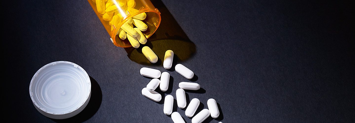 Pills spilling out of a prescription bottle.