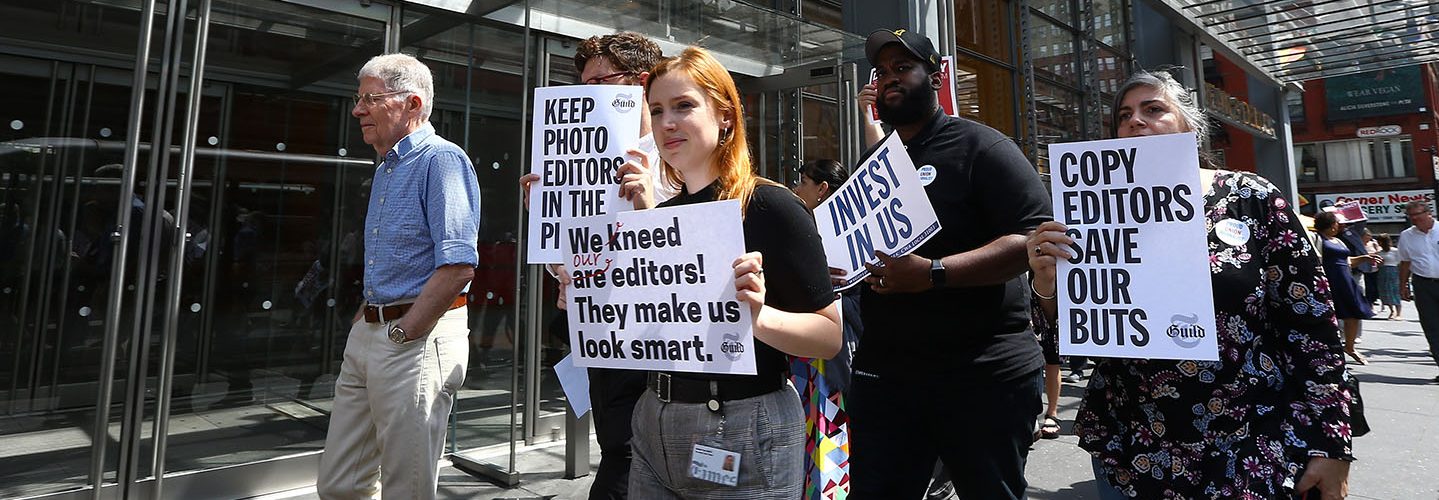 New York Times (NYT) employees hold banners during a temporary strike against downsizing and dismissal plans of the NYT management outside of New York Times building in New York, United States on June 29, 2017.