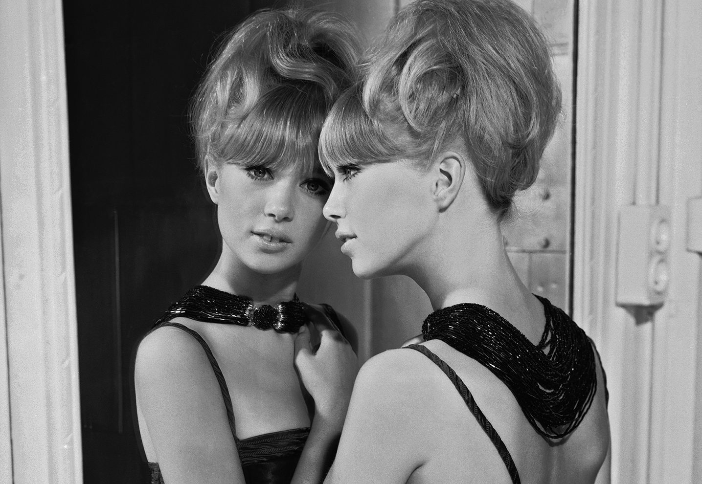 1964: Patti Boyd in a bare-shouldered evening dress and an elaborate bead necklace leans wistfully against a full-length mirror. (Photo by Chaloner Woods/Getty Images)
