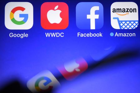 This photograph taken on September 28, 2017, shows a smartphone being operated in front of GAFA logos (acronym for Google, Apple, Facebook and Amazon web giants) as background in Hédé-Bazouges, western France. / AFP PHOTO / Damien MEYER        (Photo credit should read DAMIEN MEYER/AFP/Getty Images)