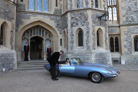 Britain's Prince Harry, Duke of Sussex, (L) opens the passenger door of an E-Type Jaguar car for his wife Meghan Markle, Duchess of Sussex, (R) as they leave Windsor Castle in Windsor on May 19, 2018 after their wedding to attend an evening reception at Frogmore House. (Steve Parsons / POOL / AFP)        (Photo credit should read STEVE PARSONS/AFP/Getty Images)