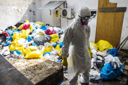 A hospital health worker stand prepares to remove garbage from Ebola patients  between wings/buildings of the Redemption  Hospital which has become a transfer and holding center to intake Ebola patients located in one of the poorest neighborhoods of Monrovia that locals call "New Kru Town on Saturday September 20, 2014 in Monrovia, Liberia. (Photo by Michel du Cille/The Washington Post via Getty Images)