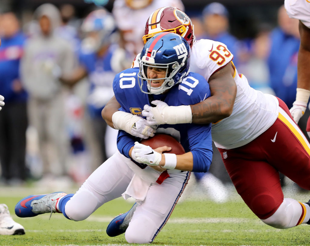 Eli Manning #10 of the New York Giants is sacked by Jonathan Allen #93 of the Washington Redskins on October 28,2018 at MetLife Stadium in East Rutherford, New Jersey.  (Photo by Elsa/Getty Images)