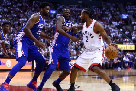 Kawhi Leonard dribbles by Joel Embiid and James Ennis III. (Vaughn Ridley/Getty)