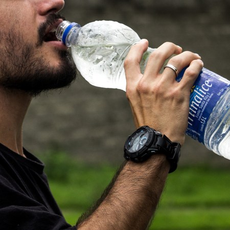 A man drinking from a plastic bottle of water. We need to stop drinking bottled water to save the planet and ourselves.