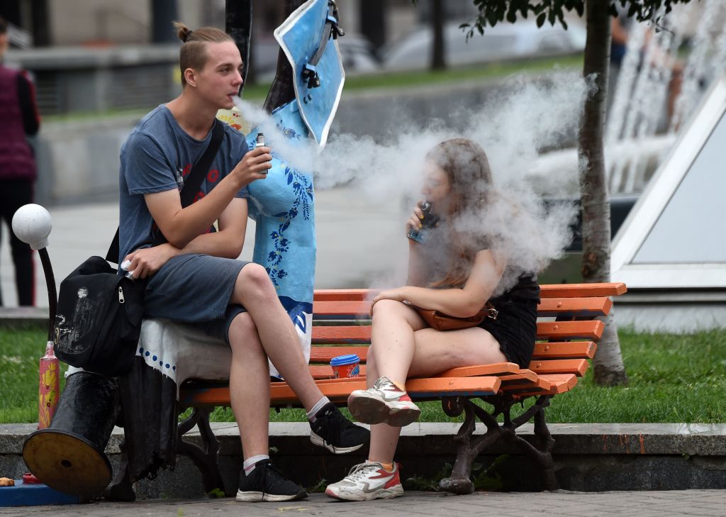 Young people smoke electronic cigarettes as they rest in the center of the Ukrainian capital of Kiev, on August 15, 2019. (Photo by Sergei SUPINSKY / AFP)        (Photo credit should read SERGEI SUPINSKY/AFP/Getty Images)
