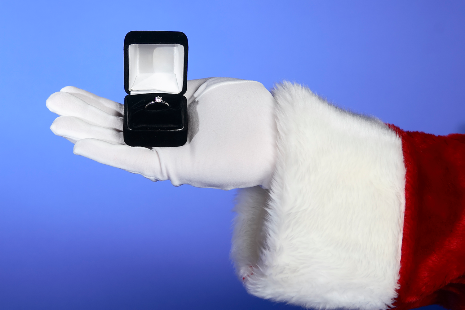 A man holds an engagement ring box behind his back