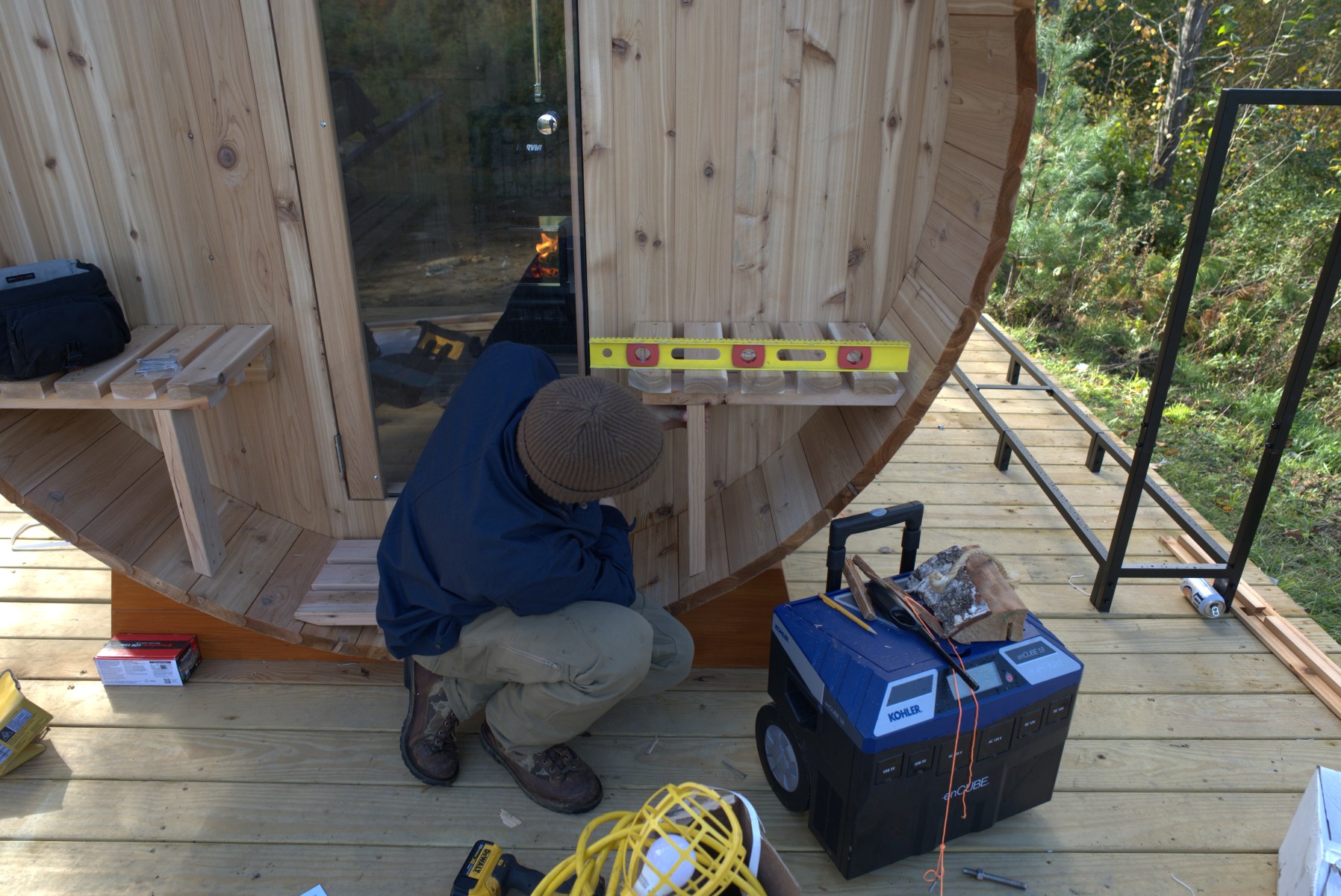 <strong>Installing the Accessories</strong><br>“This is just the finishing touches, stuff like a sand timer, fire extinguisher, robe hooks and exterior seats. Since mine is far from the house, I put a fire extinguisher in a little contained box. Just in case — you're in a wood-burning sauna. It's made of wood, so if something happens, it probably happens fast. A timer is always a good idea. There are some hooks on the outside for robes and clothes. You can also put these exterior benches outside that let you cool off. Just customize it, make it your own and put on the finishing touches.”