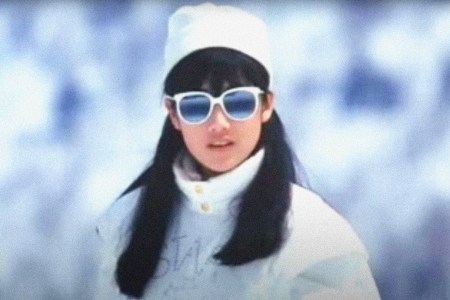 A Japanese woman poses on a ski slope.