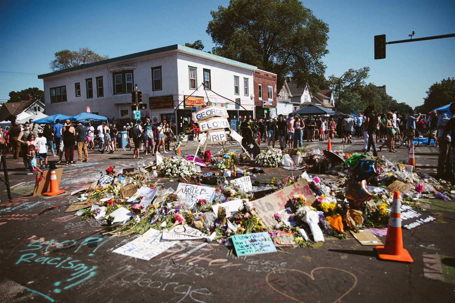 Community members protect this flower memorial at the intersection outside of Cup Foods.