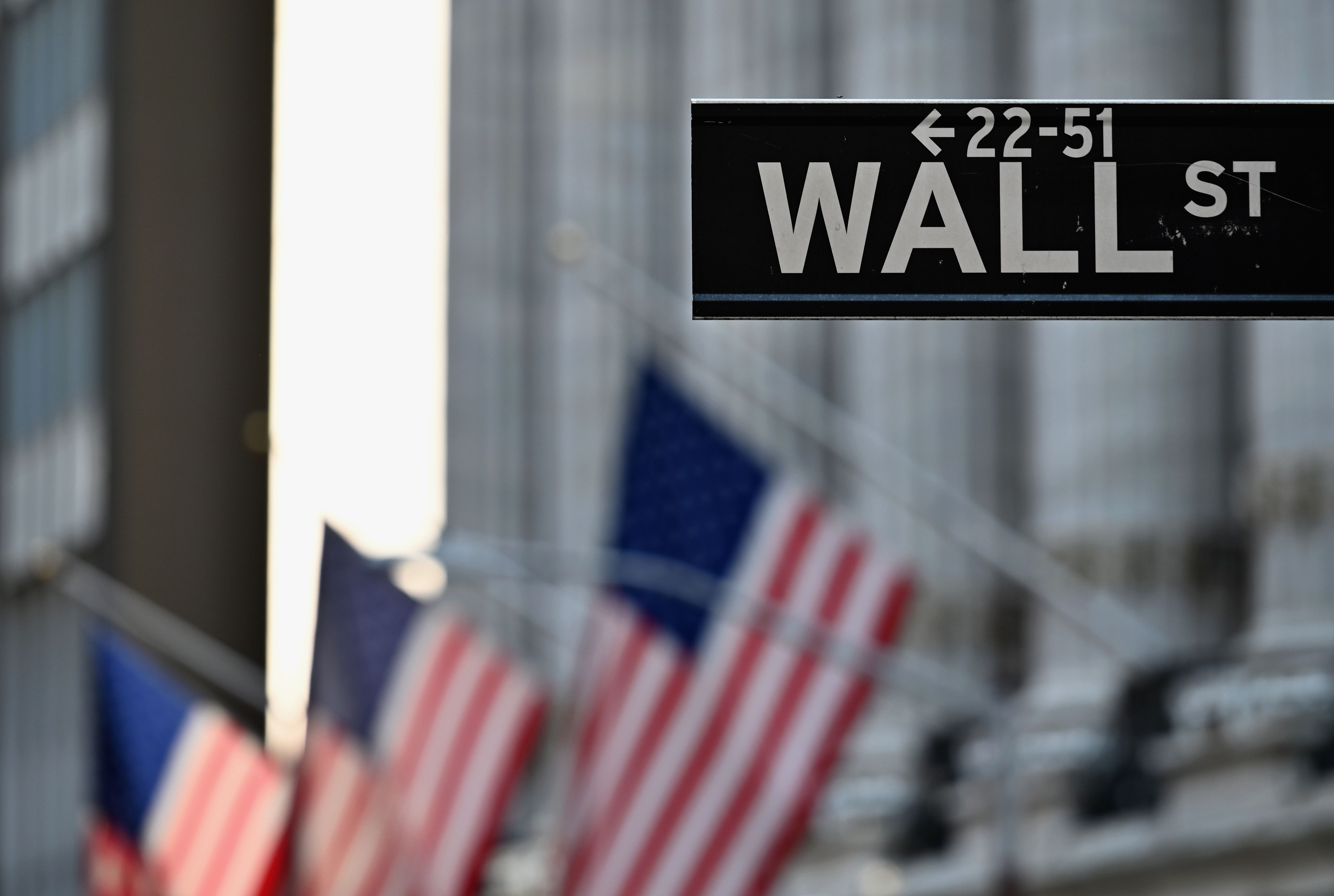 Wall Street sign in front of U.S. flags
