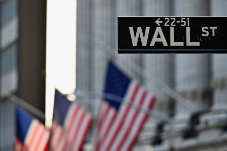 Wall Street sign in front of U.S. flags