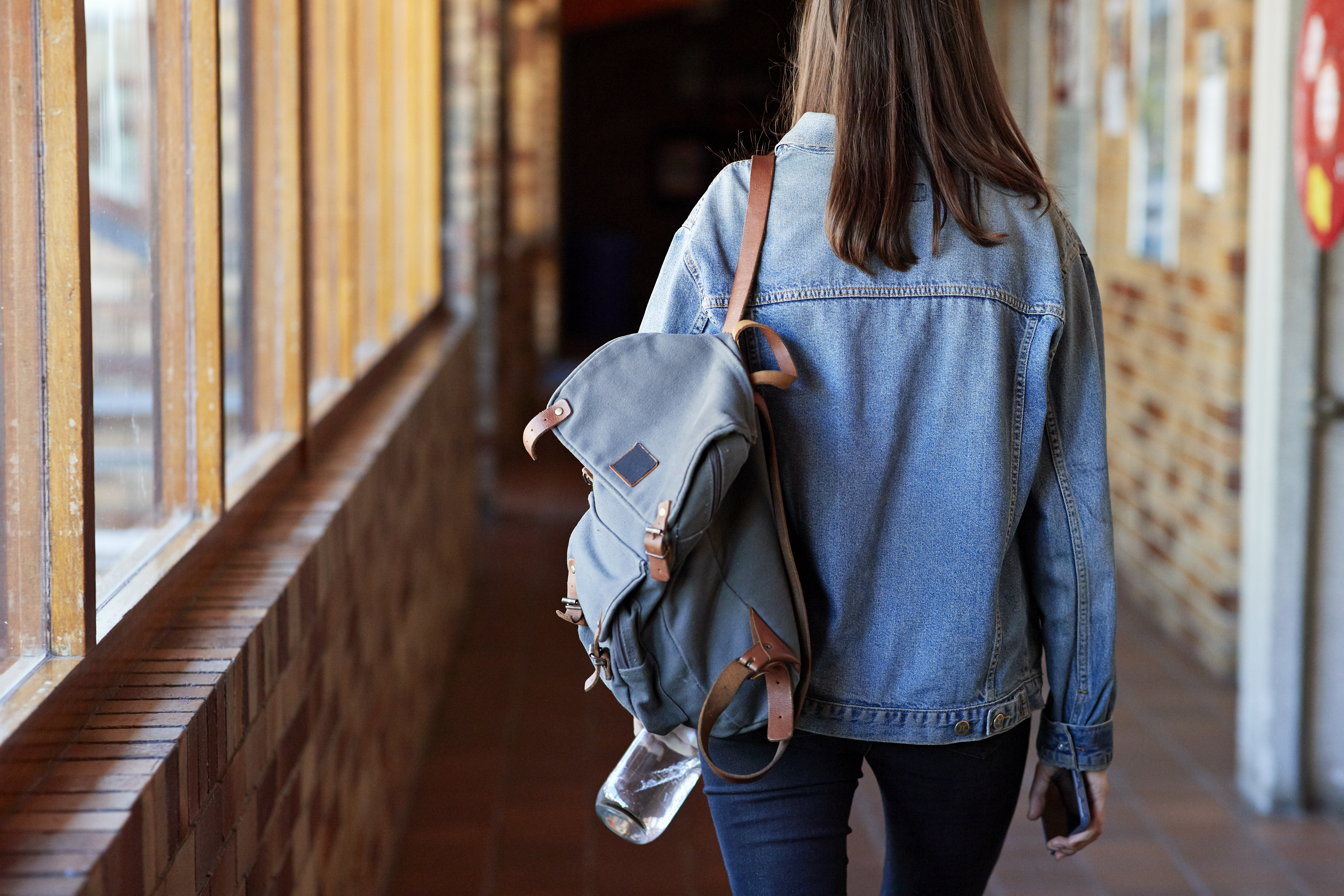 college influencer walking down a hallway with a backpack