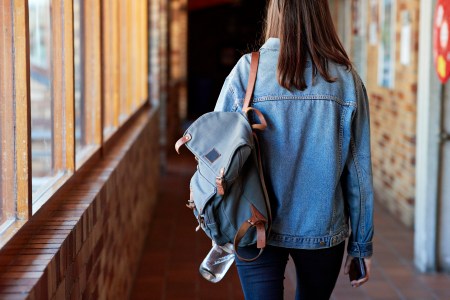 college influencer walking down a hallway with a backpack