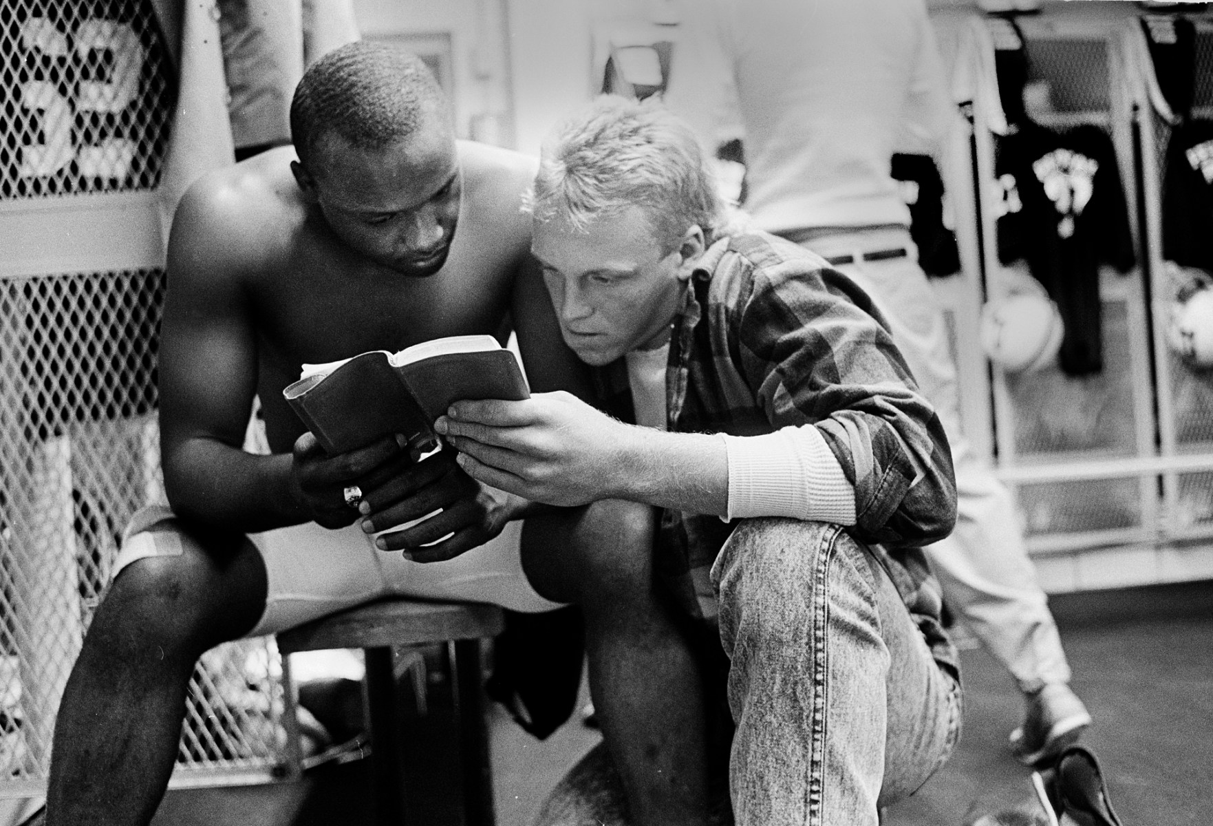 Ivory Christian (left) and Chad Payne (right) read a Bible verse in the locker room before a game. “Be strong and courageous. Do not be afraid or terrified because of them, for the Lord your God goes with you: he will never leave you nor forsake you.” (Deuteronomy 31:6)<br><br>“They called Ivory preacher because he was a religious kid and went to church on Sundays,” Clark says. “He also took part in the services. I think he may have been a deacon or something at his church. They’re reading scripture to try to find strength. This was in the locker room before they changed into their uniforms about three hours before a game.”