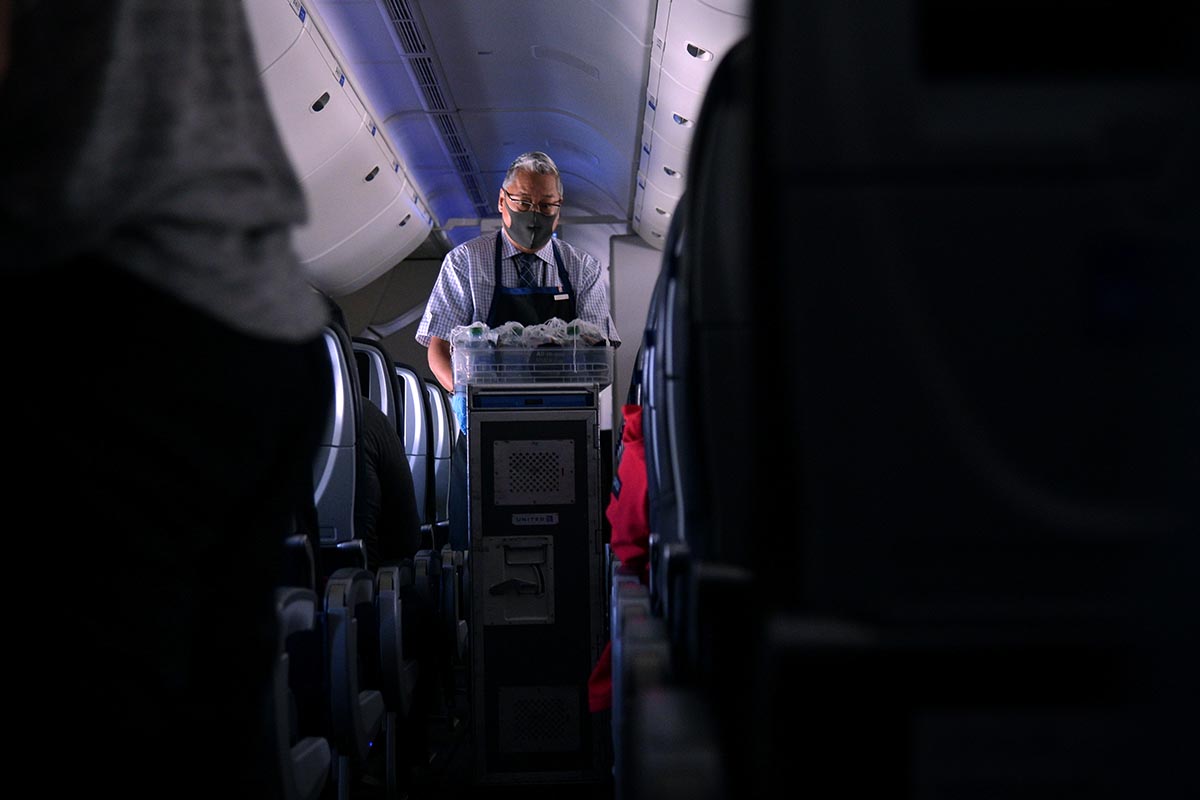 masked flight attendant on an airplane