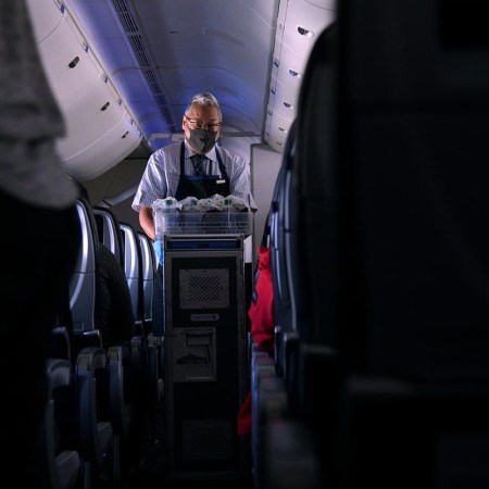 masked flight attendant on an airplane