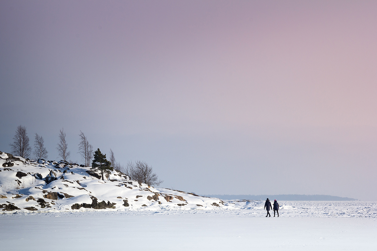 A group of adults Nordic walking across a cold beach.