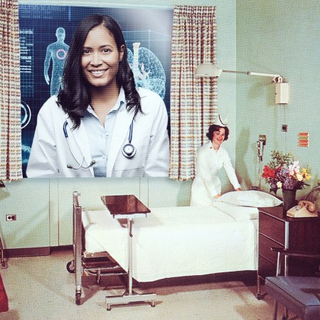 A doctor conferencing into a hospital room via a large screen
