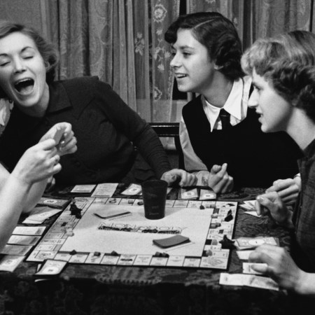 Black and white photo of actress Veronica Hurst (second from left) playing Monopoly with family members.